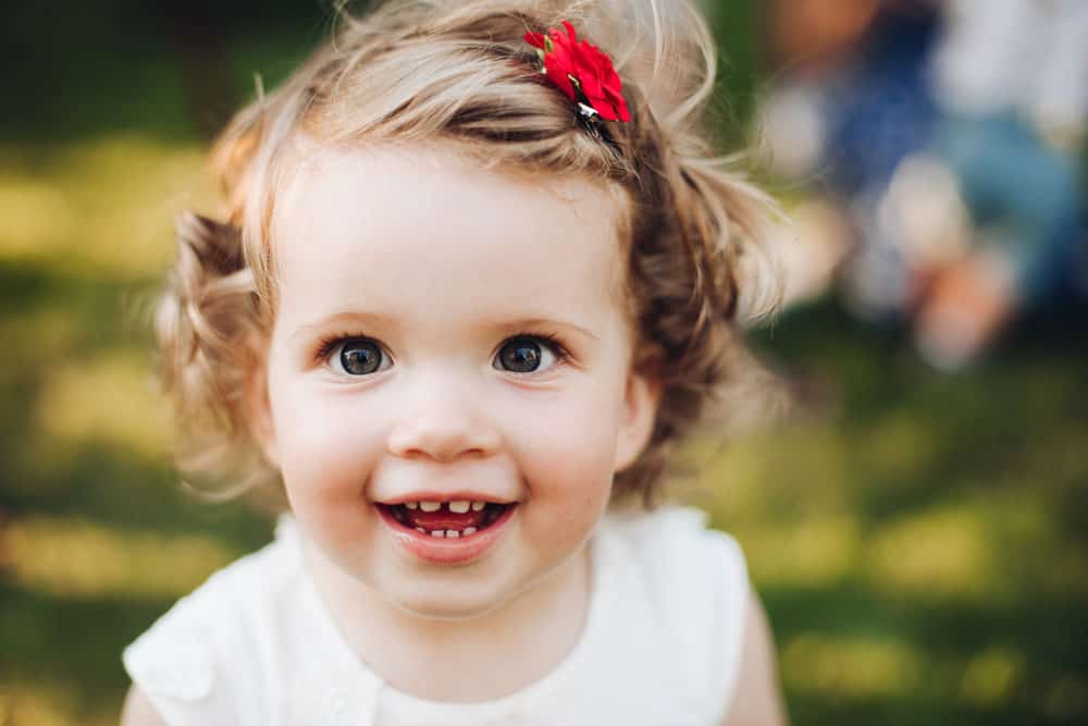 toddler girl smiling at camera for bog post on middle names for Bailey