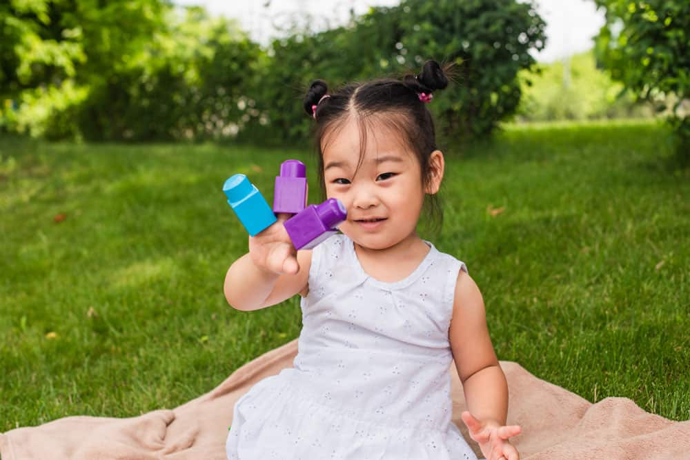 picture of toddler girl on the grass with leggos for a post on middle names for Chloe
