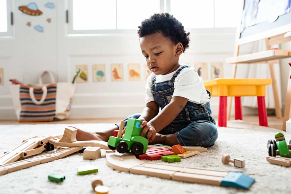 picture of a toddler boy playing with his train set in his bedroom for a post on middle names for Damian