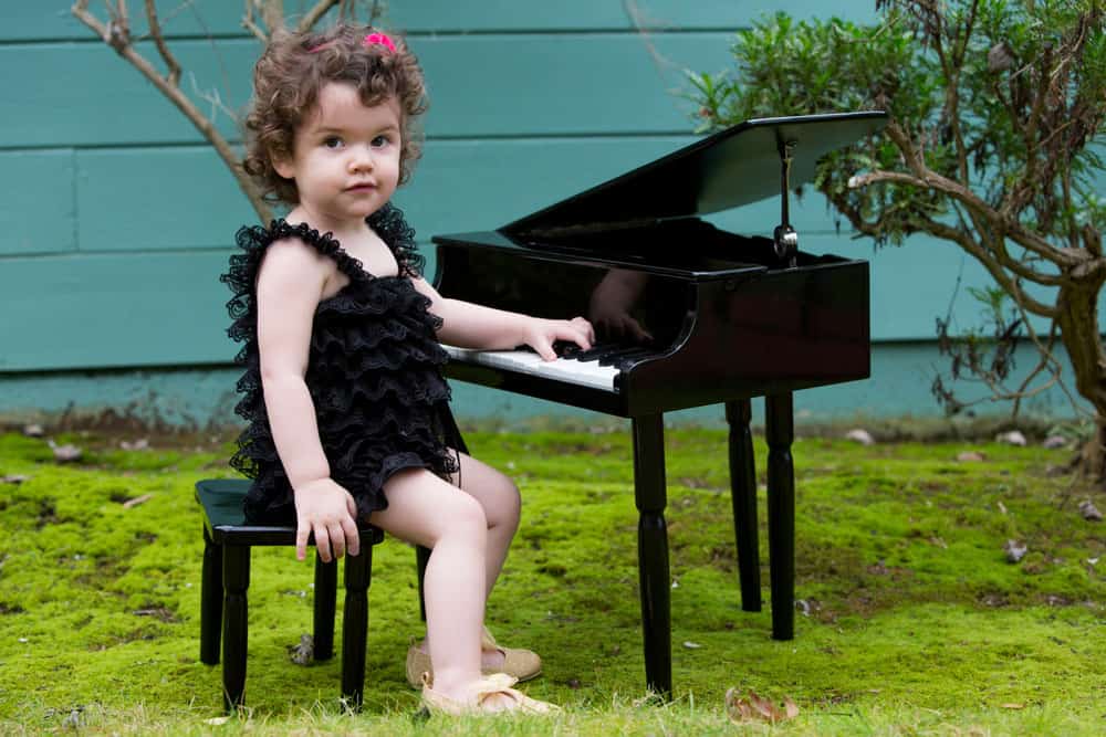 toddler girl sitting at piano for a blog post on middle names for Faith