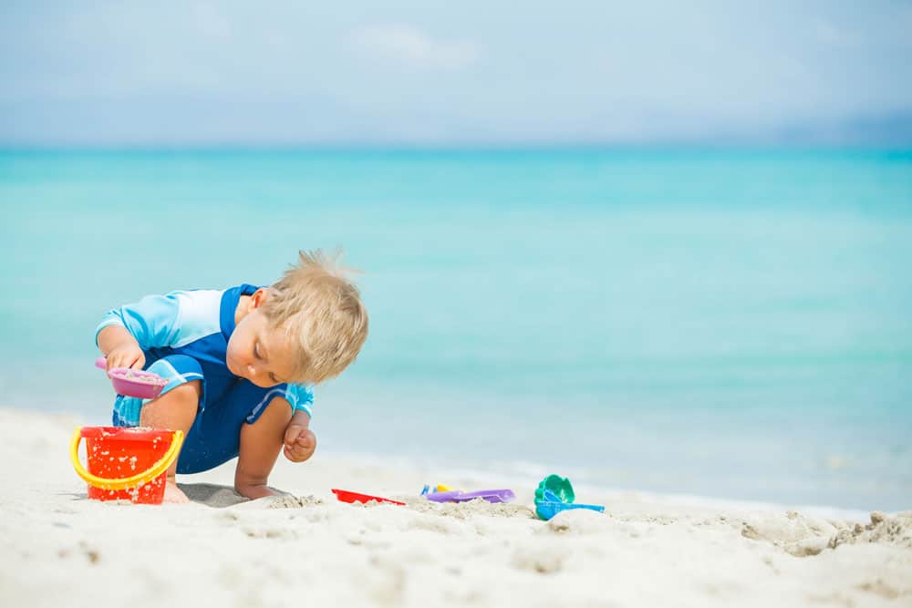 picture of toddler boy at beach with beach toys for article on middle names for Kai