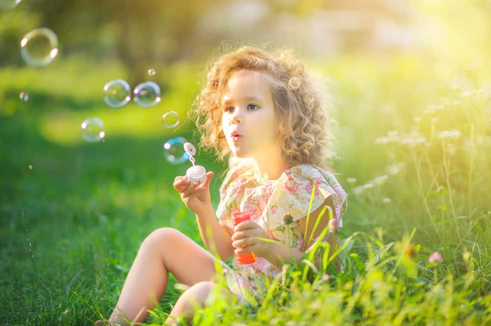 little girl in grass blowing bubbles for a post on middle names for Sophie