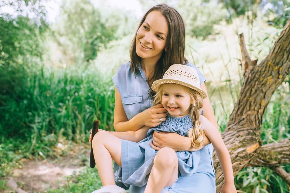 picture of mother with toddler daughter sitting in her lap wearing matching blue dresses