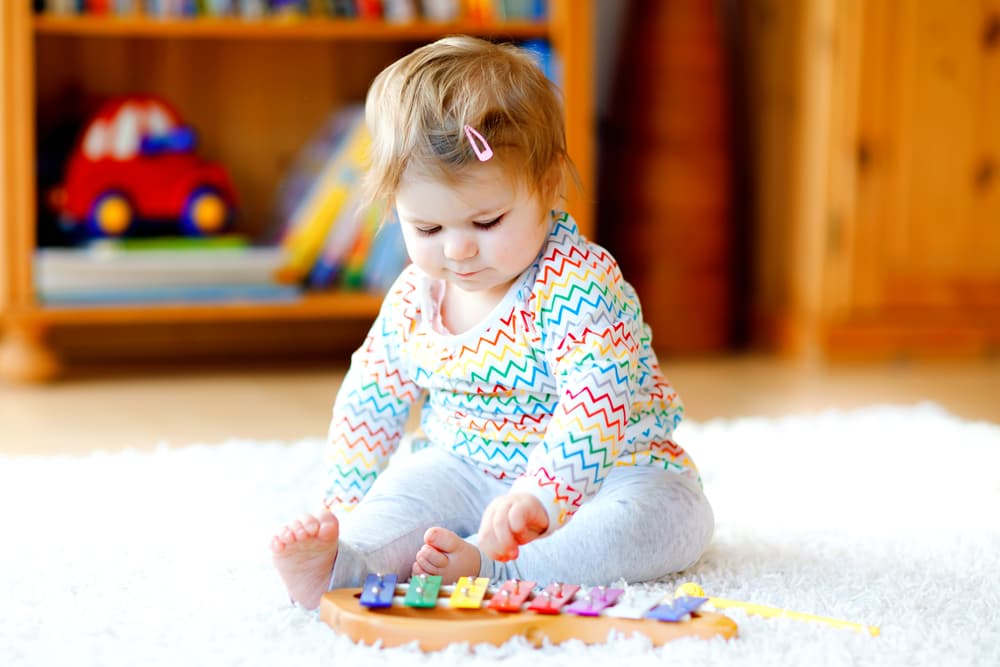 baby girl playing with instrument on the floor