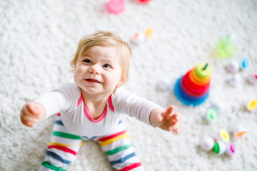 baby girl on floor playing with stacking toys