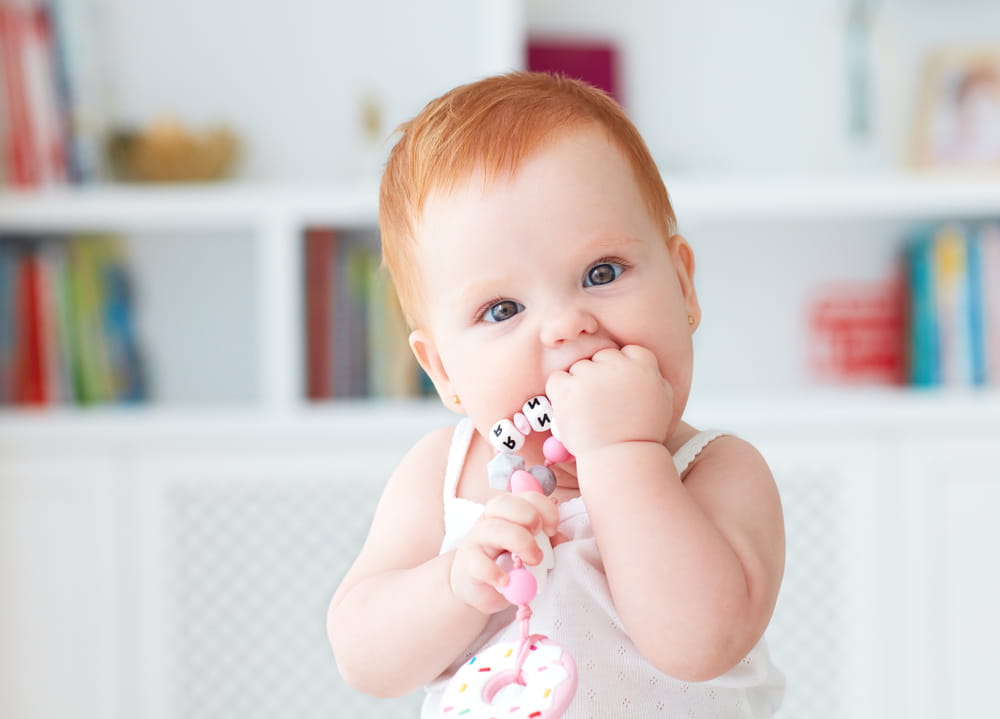 picture of baby girl chewing on teething ring