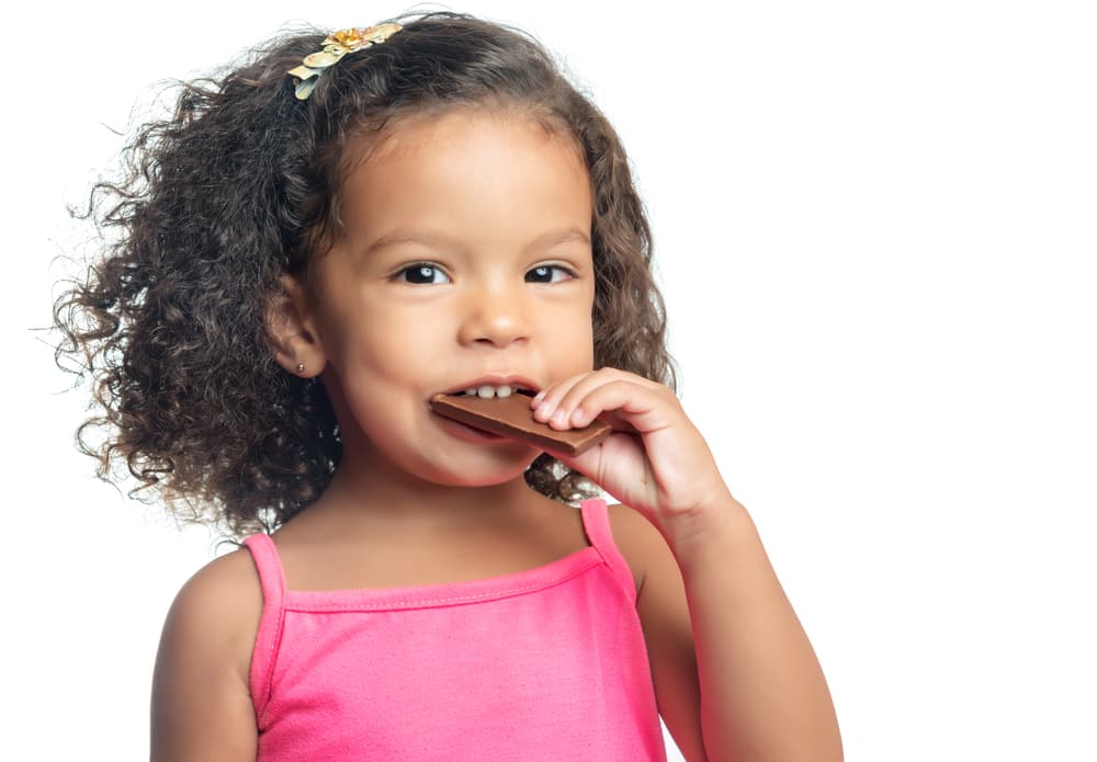 picture of little girl in pink shirt eating a chocolate bar