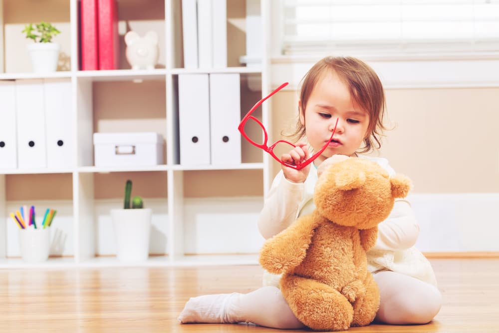 picture of toddler girl playing on the floor with a stuffed teddy bear