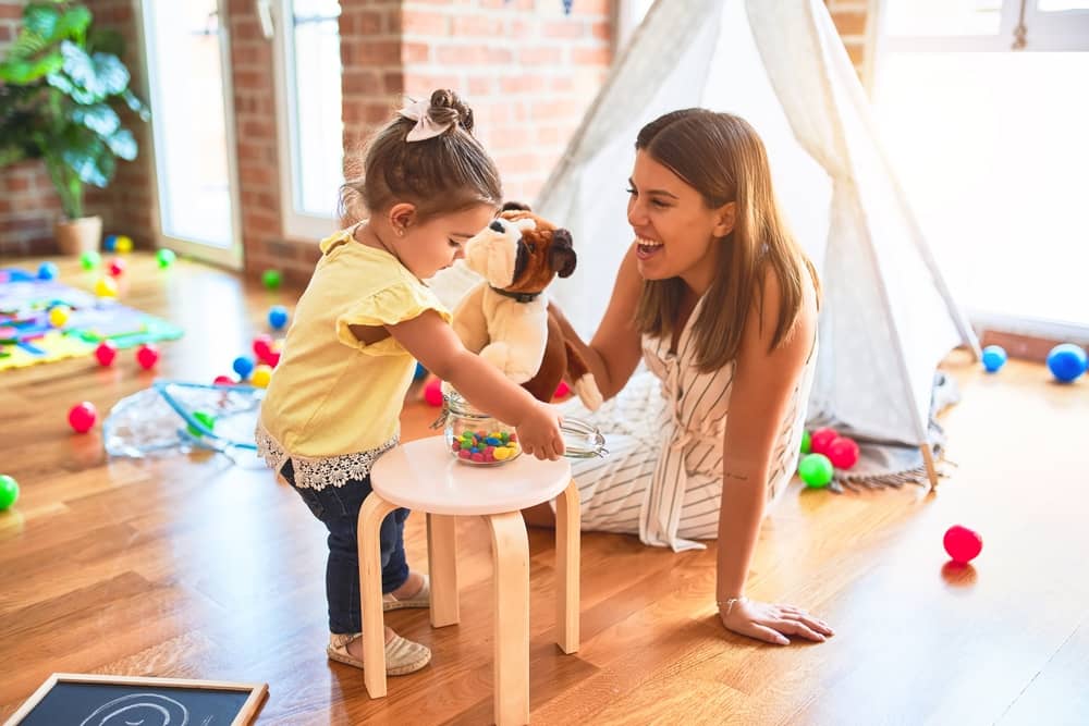 picture of toddler girl and mom playing in playroom with toys