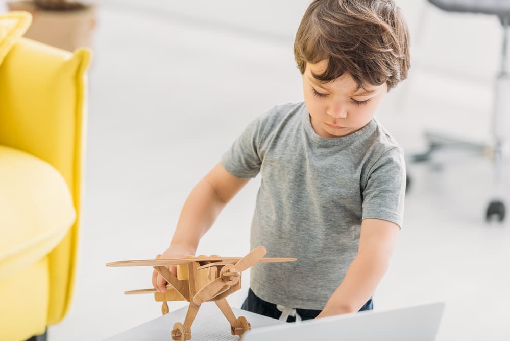 picture of toddler boy playing with wooden airplane toy