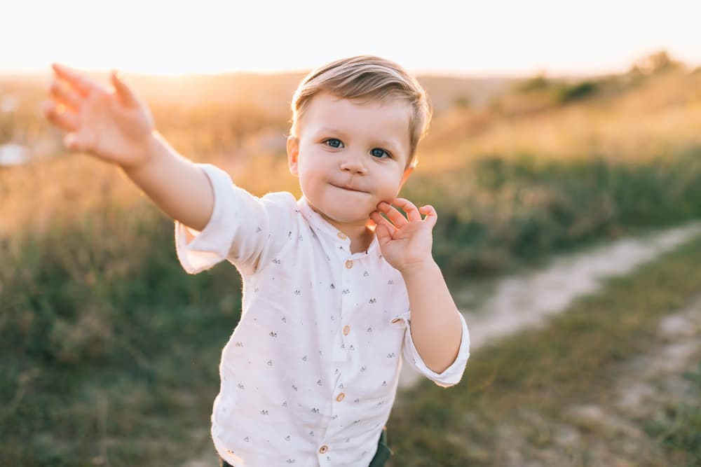 picture of little boy in white button down shirt in a field