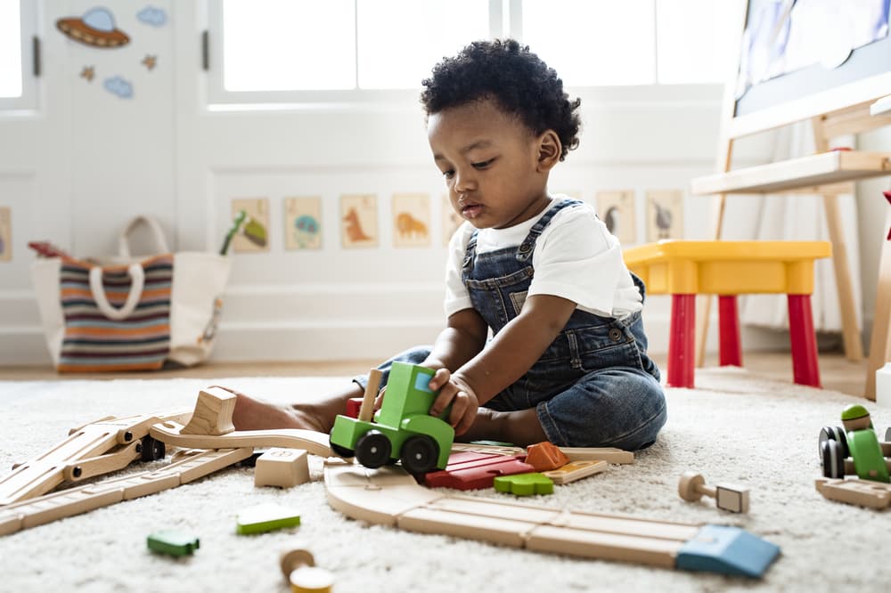 picture of toddler boy in his room playing with trains and toys