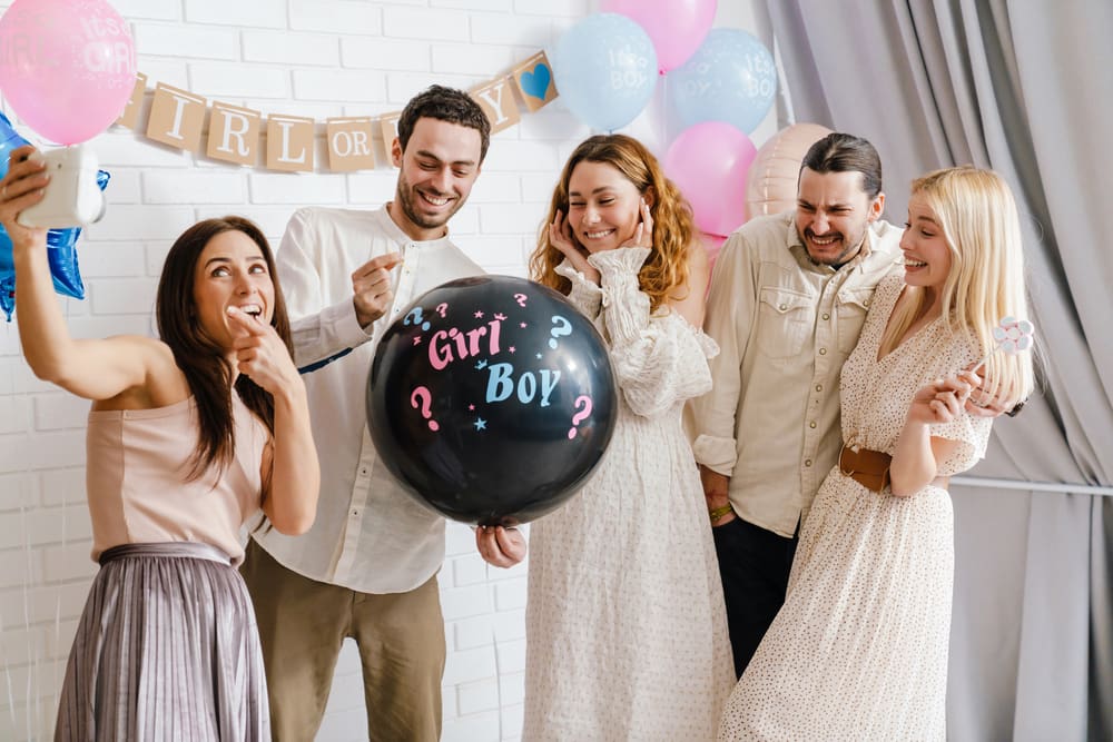 picture of five adults at a gender reveal party holding a balloon that says boy or girl?