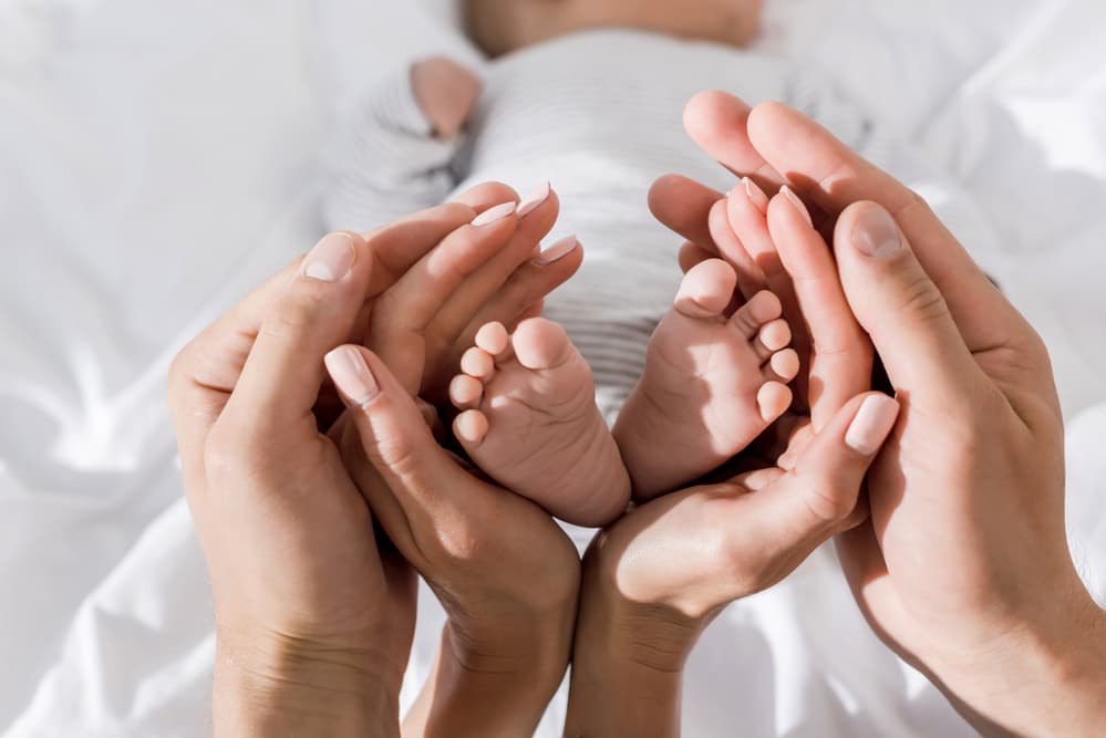 photo of baby feet encircled by mother's hands and then encircled by father's hands