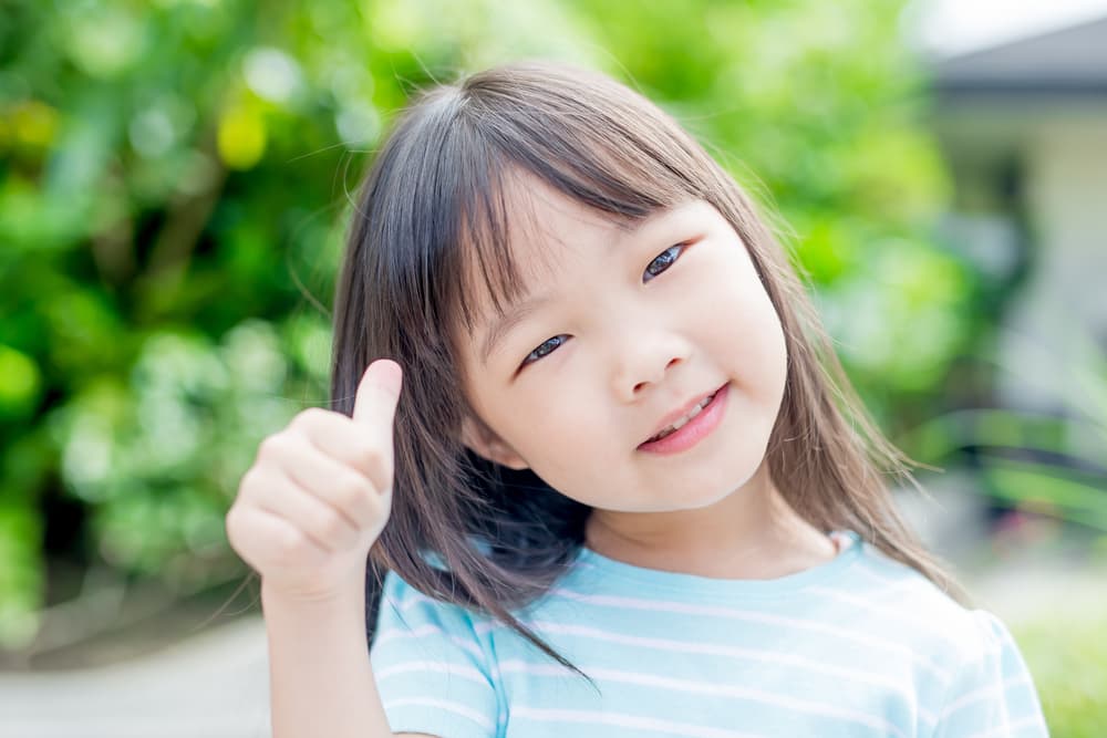 picture of toddler girl doing a thumbs up sign with her hand