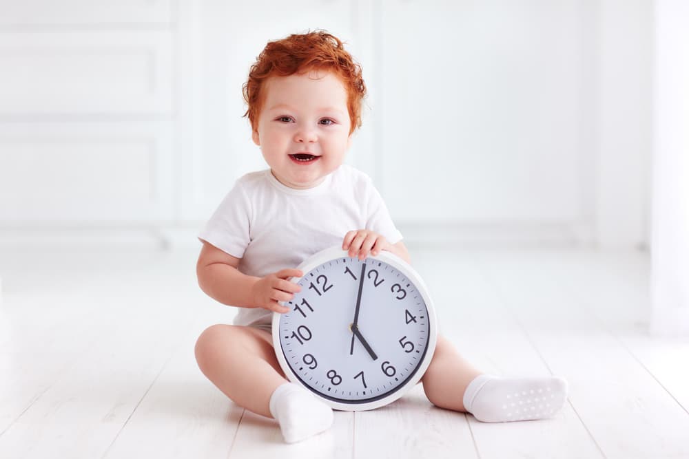 picture of toddler boy sitting on ground holding a clock
