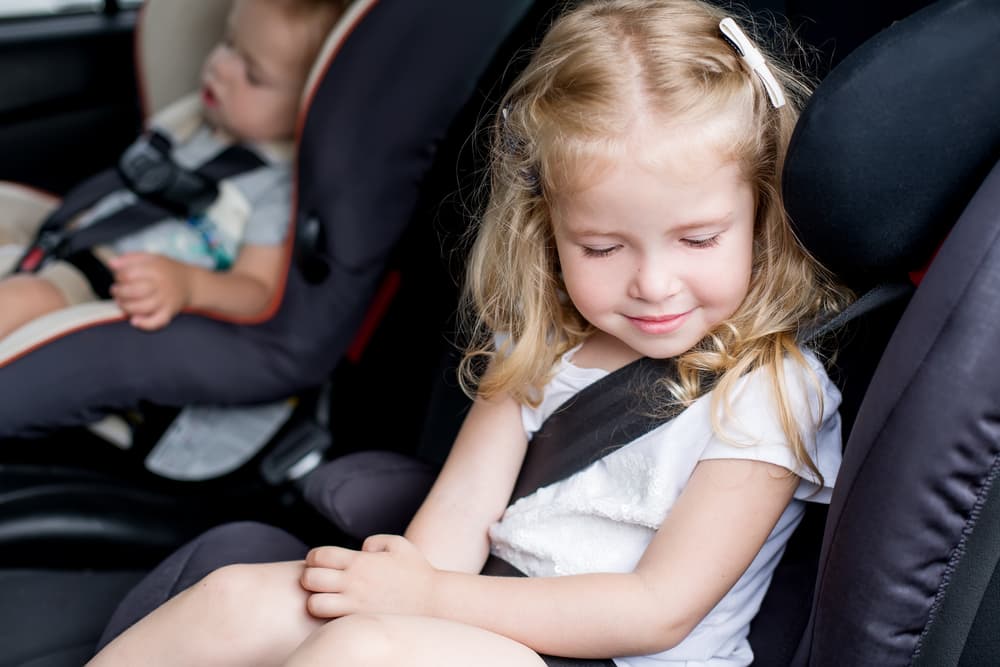 picture of toddler girl and baby in car seats