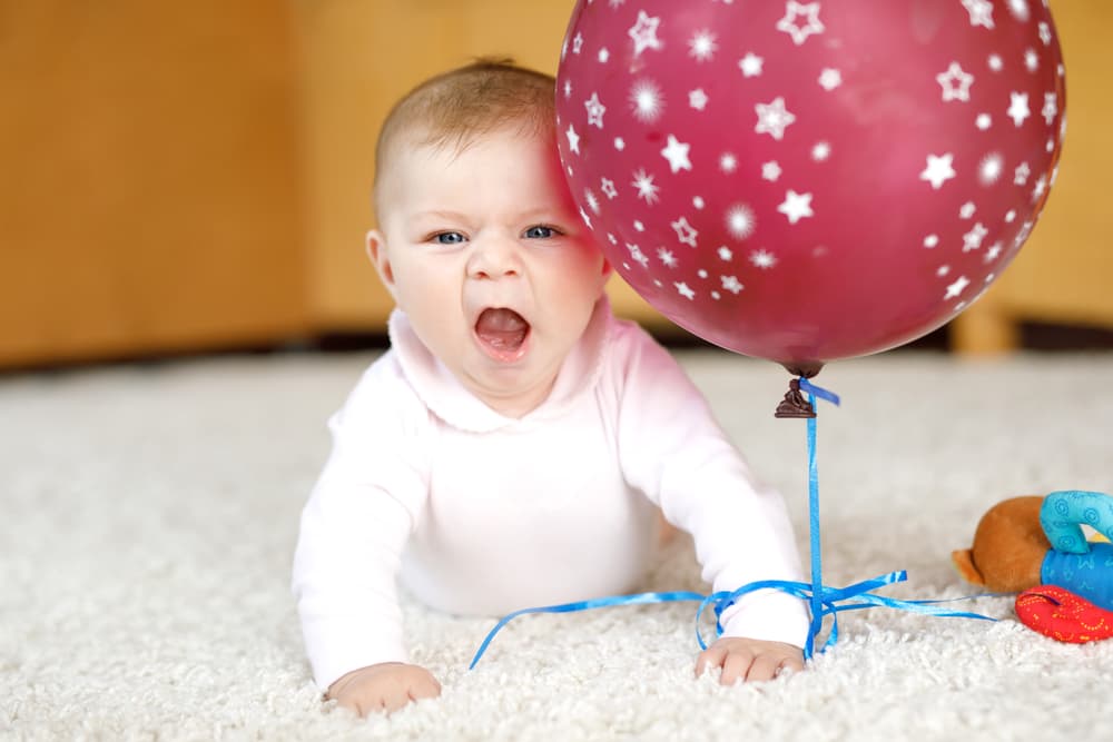 picture of baby girl on ground holding balloon